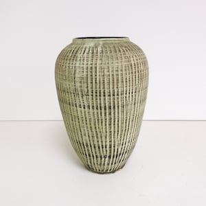 May include: A green ceramic vase with a woven pattern. The vase has a rounded body and a narrow opening.