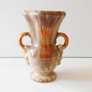 以下が含まれることがあります： 2つの取っ手のある茶色と白の陶器の花瓶。花瓶は渦巻き模様とオレンジ色のアクセントがあります。