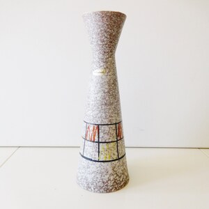 Könnte beinhalten: Eine graue Keramikvase mit einem geometrischen Muster in Braun, Gelb und Rot. Die Vase hat einen schmalen Hals und einen breiten Boden.