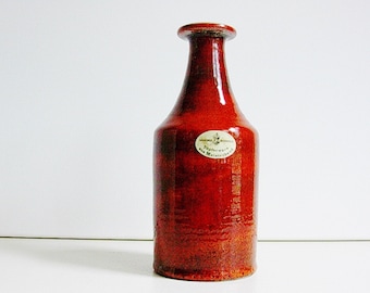 Puede incluir: Un jarrón de cerámica rojo con una etiqueta que dice "Handwerk Pottery Meisterwerk".