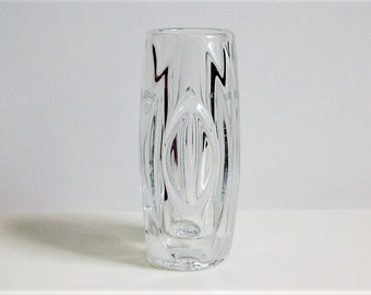 May include: A clear glass vase with a textured, wavy design. The vase is cylindrical in shape and has a rounded base.