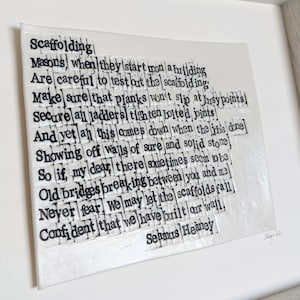 Könnte beinhalten: Weiß gerahmtes Kunstwerk mit einem Gedicht von Seamus Heaney, "Scaffolding", in schwarzem Text. Das Kunstwerk ist signiert und datiert. Der Text ist in einem rechteckigen Format angeordnet.