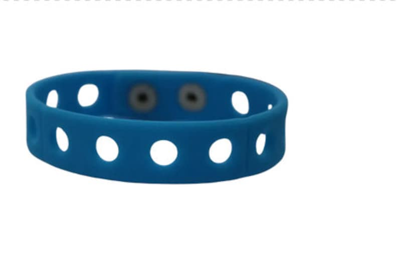 May include: A bright blue silicone wristband featuring a series of evenly spaced circular cutouts along the entire length of the band. The wristband includes two small, circular, metallic-colored snap fasteners positioned near the center.