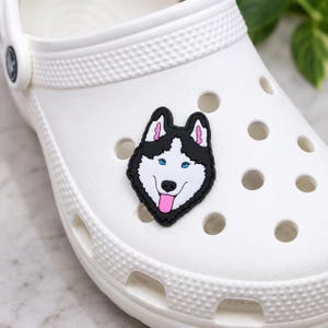Black and white Husky dog shoe charm with blue eyes, pink ears and pink tongue, approximately 1 inch long.