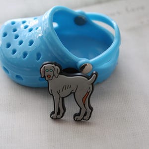 May include: A gray and white Weimaraner dog charm, a popular accessory for shoes, is attached to a blue plastic shoe.