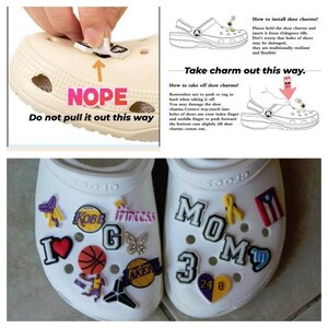May include: Two pairs of white clogs with various colorful shoe charms attached. The charms include a basketball, a heart, a butterfly, a crown, a yellow ribbon, a Puerto Rican flag, and a letter 'G'. The text 'NOPE' is written on one clog, and the text 'MOM 3' is written on the other clog. The text 'Do not pull it out this way' is written on the clog with the 'NOPE' text. The text 'Take charm out this way' is written on the clog with the 'MOM 3' text.