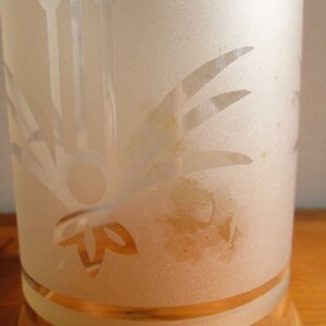May include: A frosted glass vase with a floral design etched into the surface. The vase has a clear glass base and a frosted glass top. The vase is decorated with a floral design that includes leaves and stems.