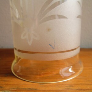 May include: A frosted glass vase with a floral design etched into the surface. The vase has a clear glass base.