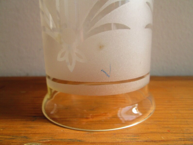 May include: A frosted glass vase with a floral design etched into the surface. The vase has a clear glass base.