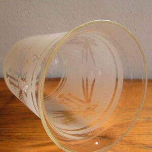 May include: A clear glass vase with a frosted design of a stylised plant. The vase has a wide mouth and a rounded bottom.