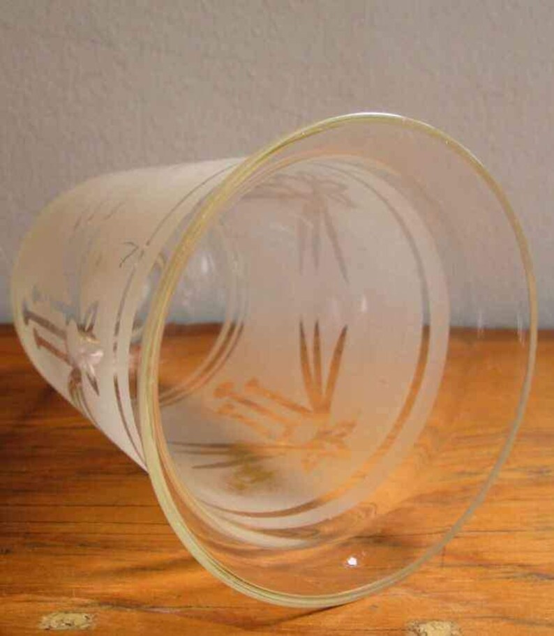 May include: A clear glass vase with a frosted design of a stylised plant. The vase has a wide mouth and a rounded bottom.