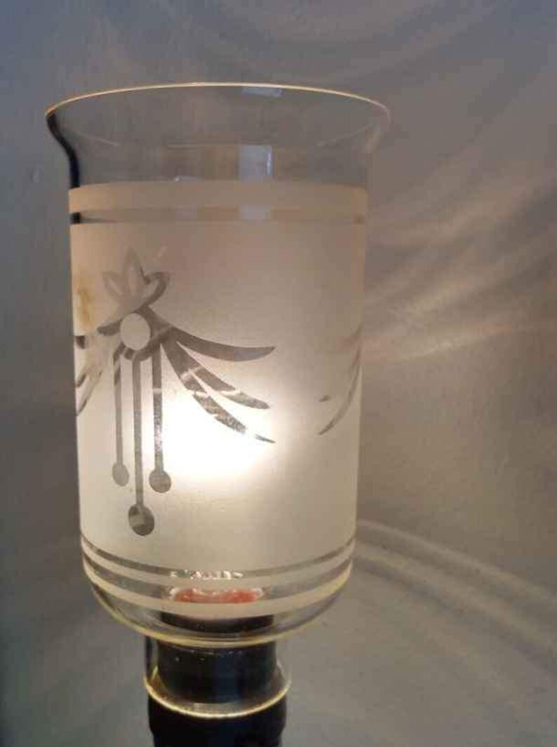 May include: A frosted glass lampshade with a silver etched design of a stylised flower and leaves. The lampshade is clear at the top and bottom, revealing the light bulb inside.