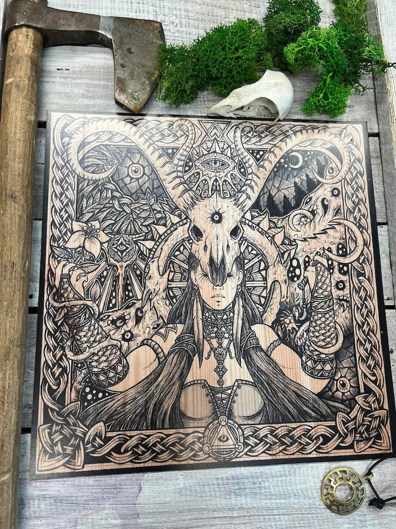 May include: A black and white woodblock print of a woman with a skull headdress and a Celtic knot border. The woman is surrounded by intricate designs and symbols.