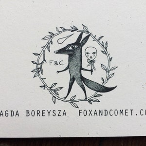 Pu&ograve; includere: Illustrazione in bianco e nero di una volpe che tiene una bambola con un cerchio di foglie intorno a loro. Il testo "F&C" e "FOXANDCOMET.COM" sono anche inclusi nell'immagine.