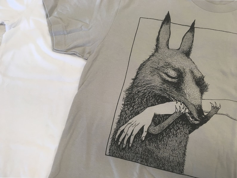 May include: A gray t-shirt with a black and white illustration of a creature with large ears biting a human arm.