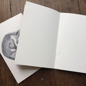 Pu&ograve; includere: Un quaderno vuoto con un disegno di una volpe addormentata sulla copertina.