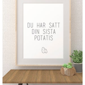 Op de afbeelding: Een ingelijst print met de tekst "DU HAR SAT DIN SISTA POTATIS" in zwarte tekst op een witte achtergrond. Een eenvoudige lijntekening van twee aardappelen bevindt zich onder de tekst.