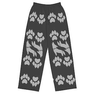 May include: Black pajama pants with a repeating pattern of light gray paw prints and wolf silhouettes. The pants have an elastic waistband and a loose, comfortable fit. The design is symmetrical, with the paw prints and wolf shapes evenly spaced.