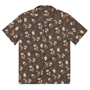 Puede incluir: Camisa marrón de manga corta con un estampado de temática cafetera. El diseño presenta tazas de café, bebidas heladas, granos de café y una ardilla de dibujos animados. La camisa tiene un cuello clásico y botones negros.