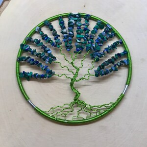 May include: A green wire tree of life wall hanging with blue and green gemstone leaves.