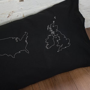 Puede incluir: Una almohada negra con contornos bordados en blanco de los Estados Unidos y el Reino Unido.