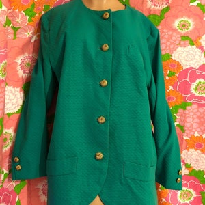 May include: A teal green blazer with a round neckline and gold buttons. The blazer has a textured fabric and two pockets.
