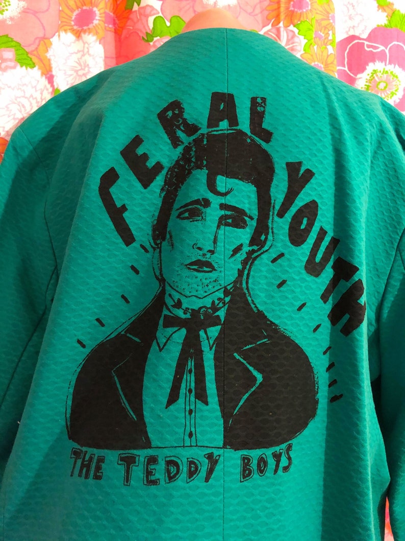 May include: A teal green jacket with a black graphic print of a man with the text "Feral Youth The Teddy Boys" on the back.