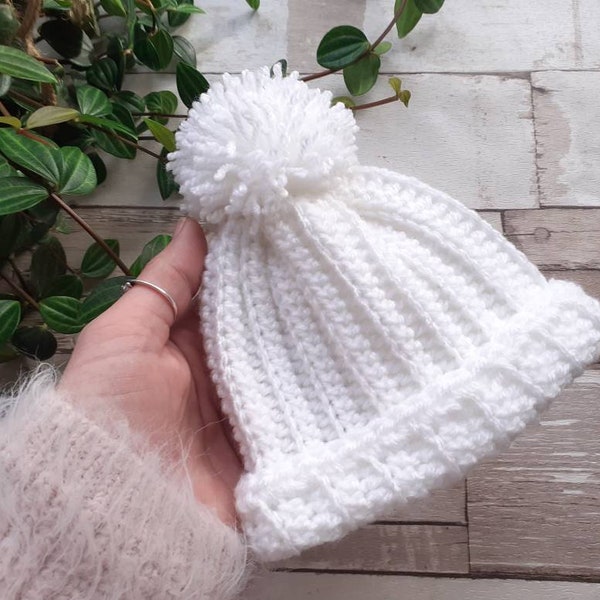 Handmade white baby pom pom hat, baby wear and photo props.Newborn baby.