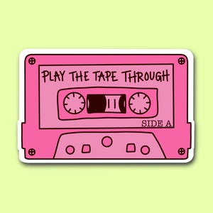 May include: A pink cassette tape sticker with the text "PLAY THE TAPE THROUGH" and "SIDE A". The sticker has a white border and a light green background. The cassette tape design includes details like the tape reels and the tape window.