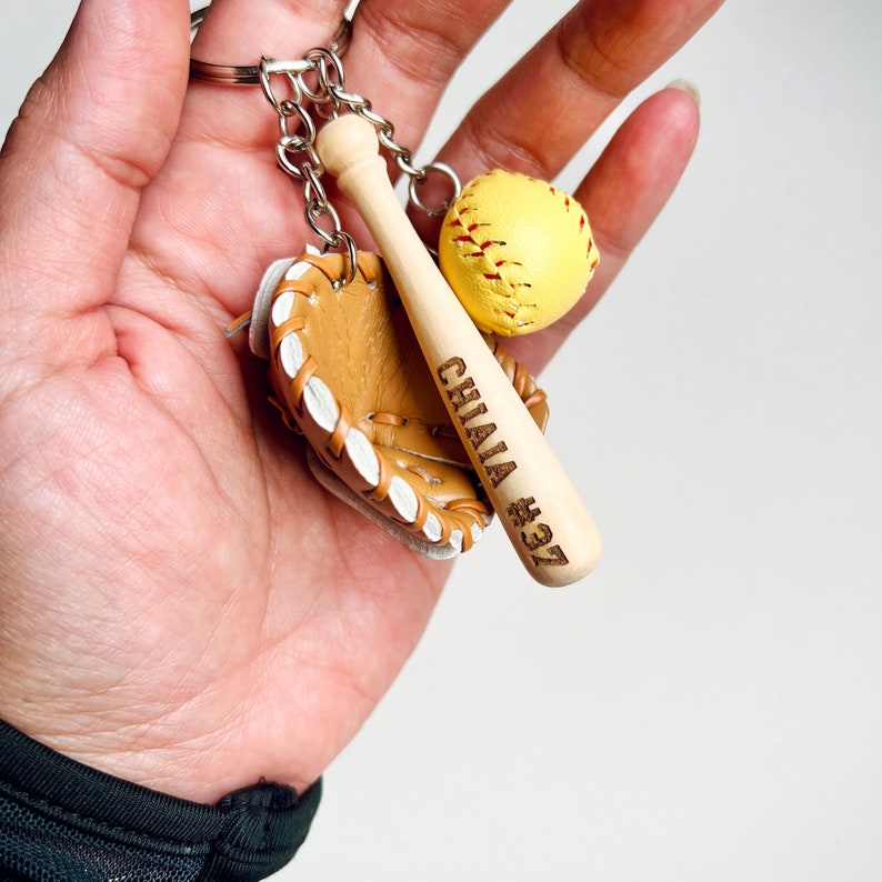 May include: A keychain featuring a miniature baseball glove, bat, and ball. The bat is personalized with the name "CHAI" and the number "#37".