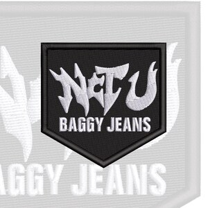 May include: A black shield-shaped embroidered patch featuring the white text "NCTU" in a stylized, sharp font above the white text "BAGGY JEANS" in a clean, sans-serif typeface. The patch has a thick black border and a textured fabric finish.