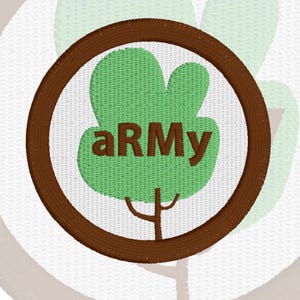May include: A circular embroidered patch featuring a brown border and a white background. In the center, a light green tree silhouette is depicted with the brown text aRMy overlaid across the middle of the tree canopy. The design is stitched.