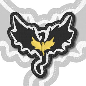 Könnte beinhalten: Ein gestickter Aufnäher mit der Silhouette eines großen schwarzen Drachen mit ausgebreiteten Flügeln und einem langen Schwanz. In der Mitte des schwarzen Drachen befindet sich eine kleinere, einfarbig gelbe Drachenfigur. Das Motiv ist weiß umrandet.