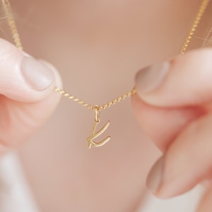 Op de afbeelding: Een gouden ketting met een delicaat, cursief letter K-hanger.