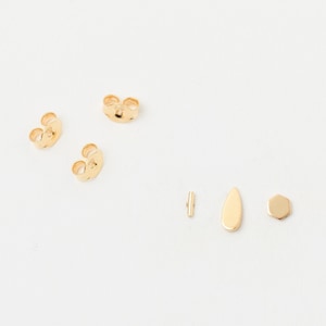 Könnte beinhalten: Ein Satz goldene Ohrringverschlüsse, eine goldene Stange, eine goldene Tropfenform und eine goldene sechseckige Form.