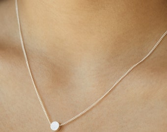May include: A silver chain necklace with a small, round pendant.