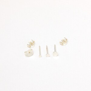 May include: A set of silver earring backs, posts, and stoppers. The earring backs are butterfly style, the posts are straight, and the stoppers are round.