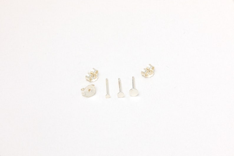 May include: A set of silver earring backs, posts, and stoppers. The earring backs are butterfly style, the posts are straight, and the stoppers are round.