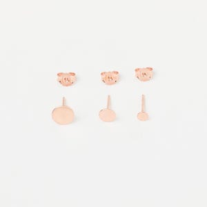 May include: Set of three rose gold stud earrings. The earrings feature a small, medium, and large round disc.