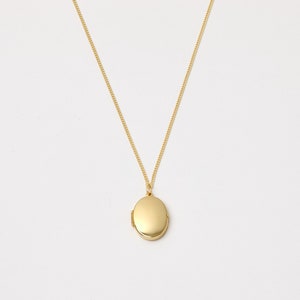 Könnte beinhalten: Eine goldene Kettenkette mit einem goldenen ovalen Anhänger.