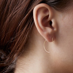 Puede incluir: Un par de pendientes de aro de oro con forma curva. Los pendientes se llevan en el lóbulo de la oreja.