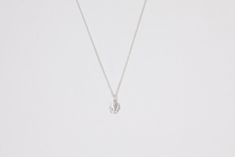 May include: A silver chain necklace with a small, textured, silver pendant.