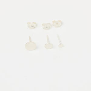 May include: Set of five silver stud earrings. Two earrings feature a small, round, silver design. Three earrings feature a larger, round, silver design.