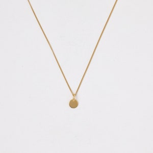 Peut inclure: Un collier en chaîne dorée avec un petit pendentif rond.