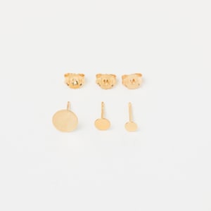 Könnte beinhalten: Set aus drei goldfarbenen Ohrsteckern. Die Ohrstecker sind rund und in drei verschiedenen Größen erhältlich.