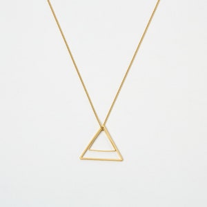 May include: A gold-toned necklace featuring a delicate chain and a geometric pendant shaped like an open triangle with a horizontal bar across the lower section. The metal has a smooth, polished finish and hangs from a thin, linked chain.