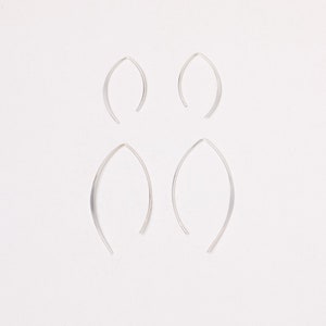 May include: Four silver hoop earrings, two smaller and two larger, on a white background.