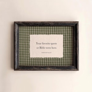 May include: A rectangular black distressed wooden frame containing a green and white plaid fabric background. Centered is a piece of off-white textured paper with deckled edges featuring the black printed text: Your favorite quote or Bible verse here. SCRIPTURE 6:24-26.