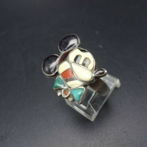 May include: A silver ring with a Mickey Mouse design made of turquoise, coral, and other stones.
