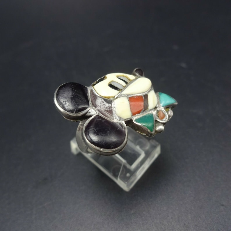 May include: A silver ring with a Mickey Mouse design made of inlaid turquoise, coral, and other stones.